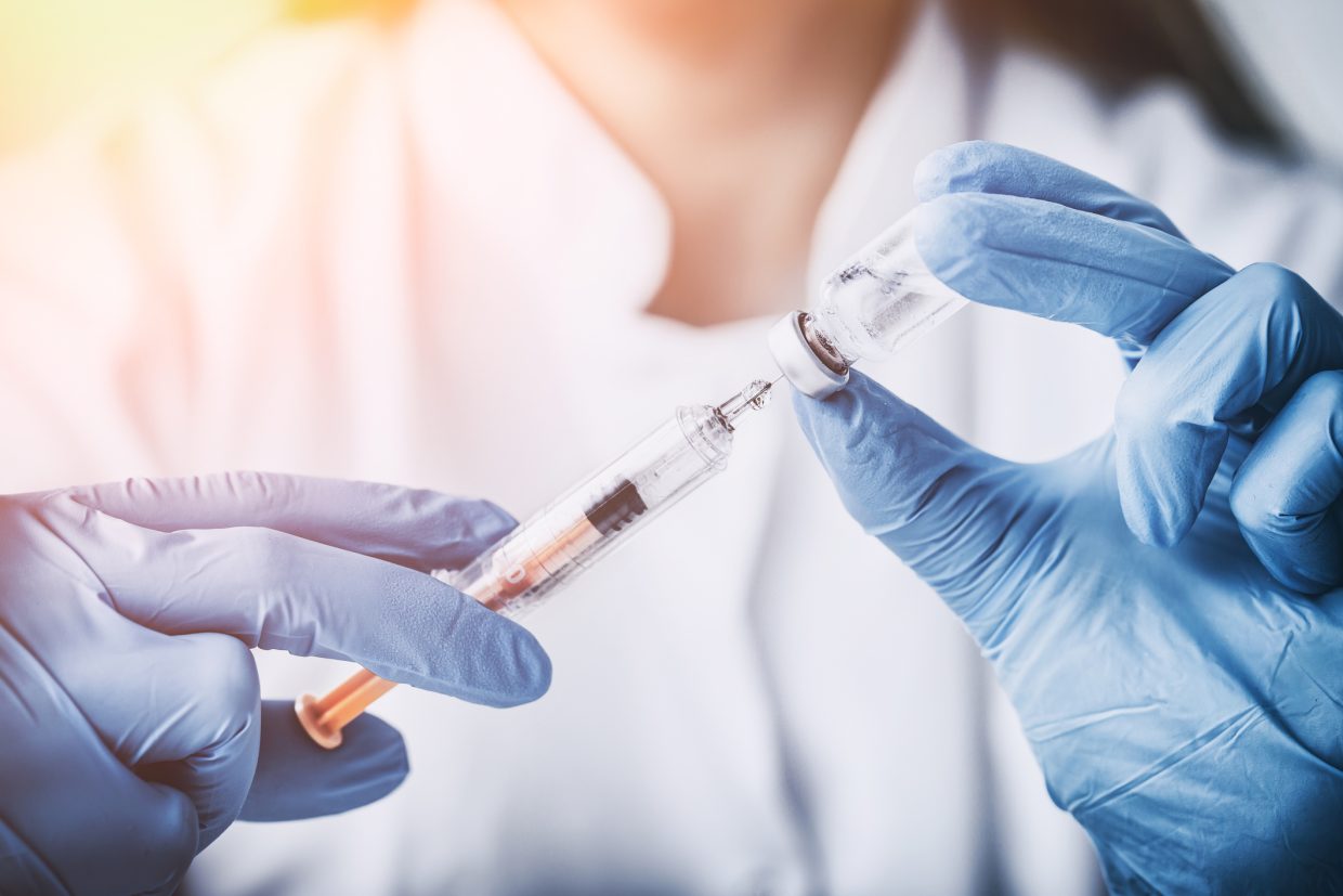 A person preparing a vaccine or injection for use.