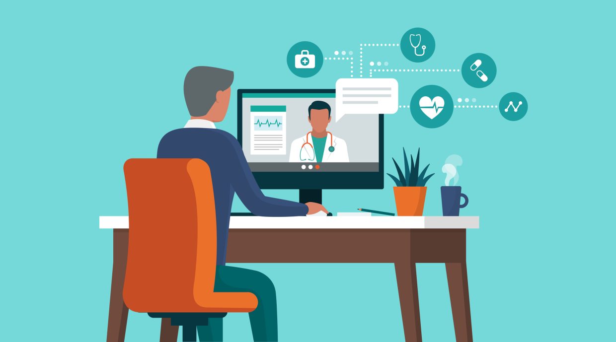 Sitting in front of a computer with a doctor on the screen talking alongside some reports. A planter and a mug of coffee are also kept on the table.